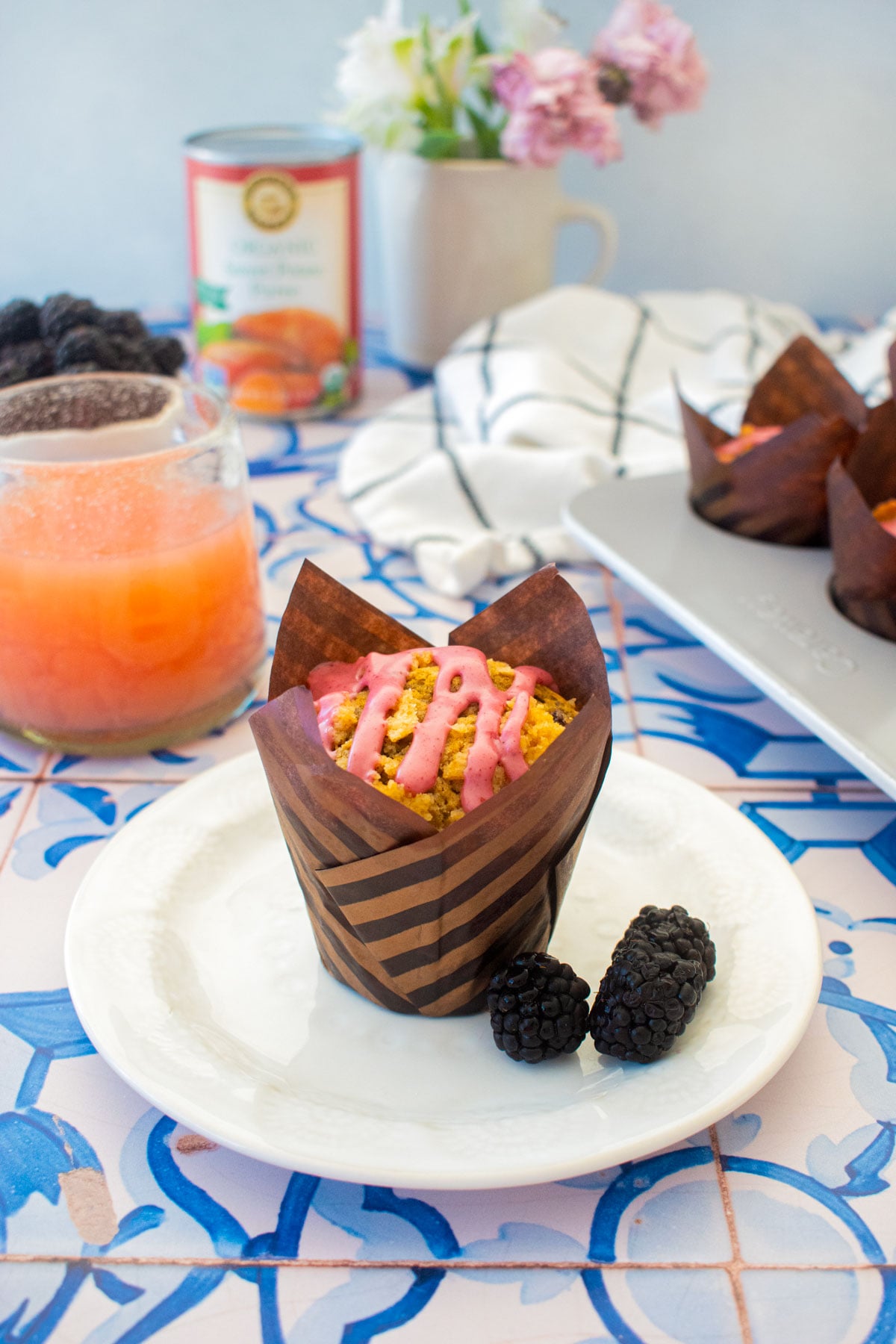 blackberry sweet potato muffin with blackberry glaze in a plate on a blue tile table.