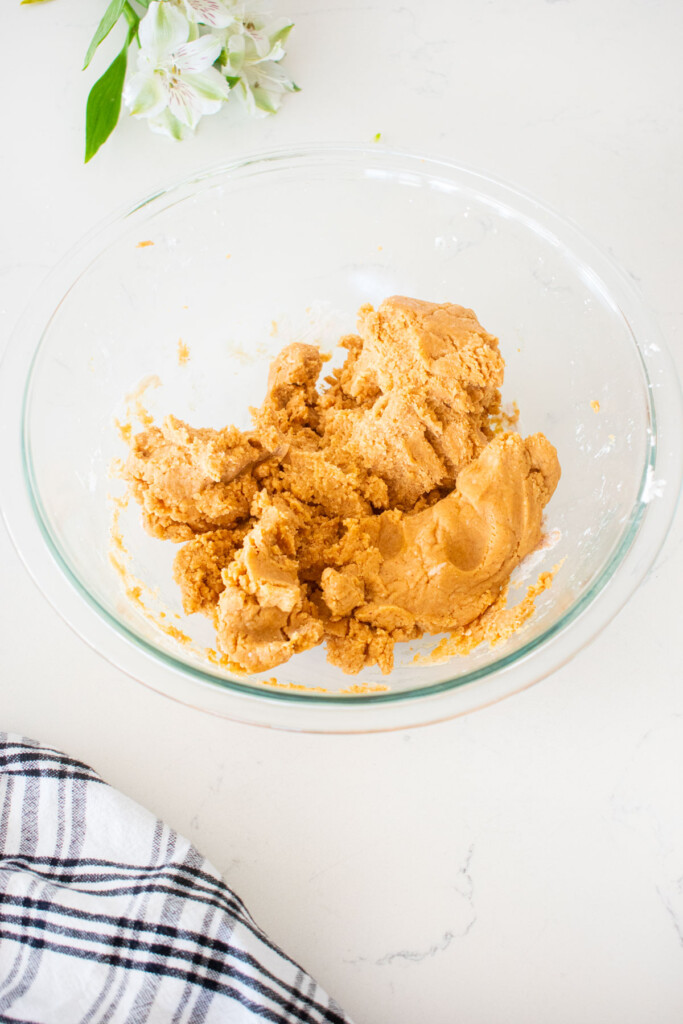 peanut butter filling in a glass mixing bowl on a white marble counter.