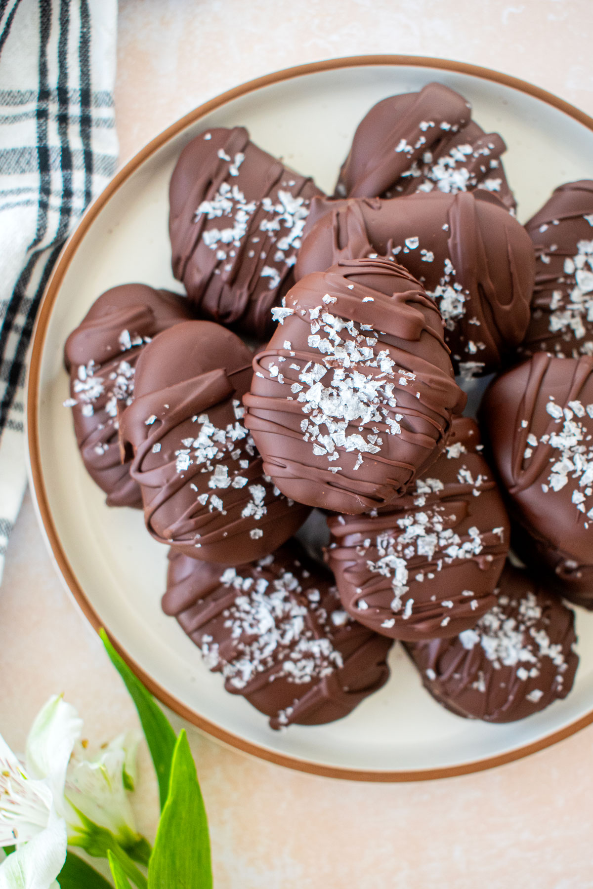 chocolate peanut butter eggs with flaky sea salt on top on a plate on a table with fresh flowers.