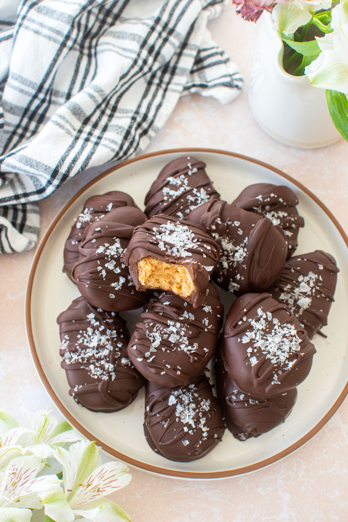 chocolate peanut butter eggs with flaky sea salt on top on a plate on a table with fresh flowers.