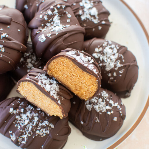chocolate peanut butter eggs with bone broth on a plate on on table with fresh flowers with one egg cut in half to reveal peanut butter center.