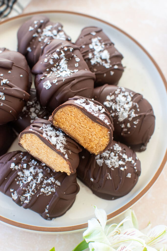 chocolate peanut butter eggs with bone broth on a plate on on table with fresh flowers with one egg cut in half to reveal peanut butter center.