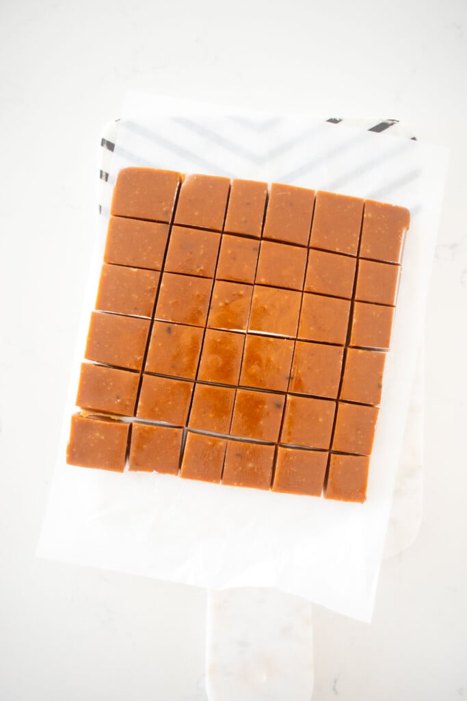 homemade chewy coffee caramel candies cut into small squares on a white marble counter.