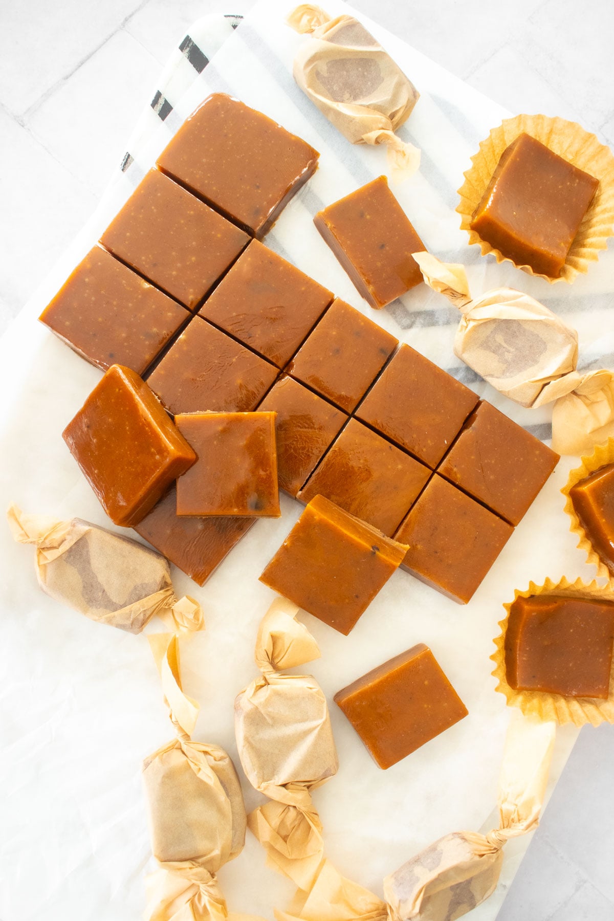 homemade chewy coffee caramel candies cut into squares on a white marble cutting board.