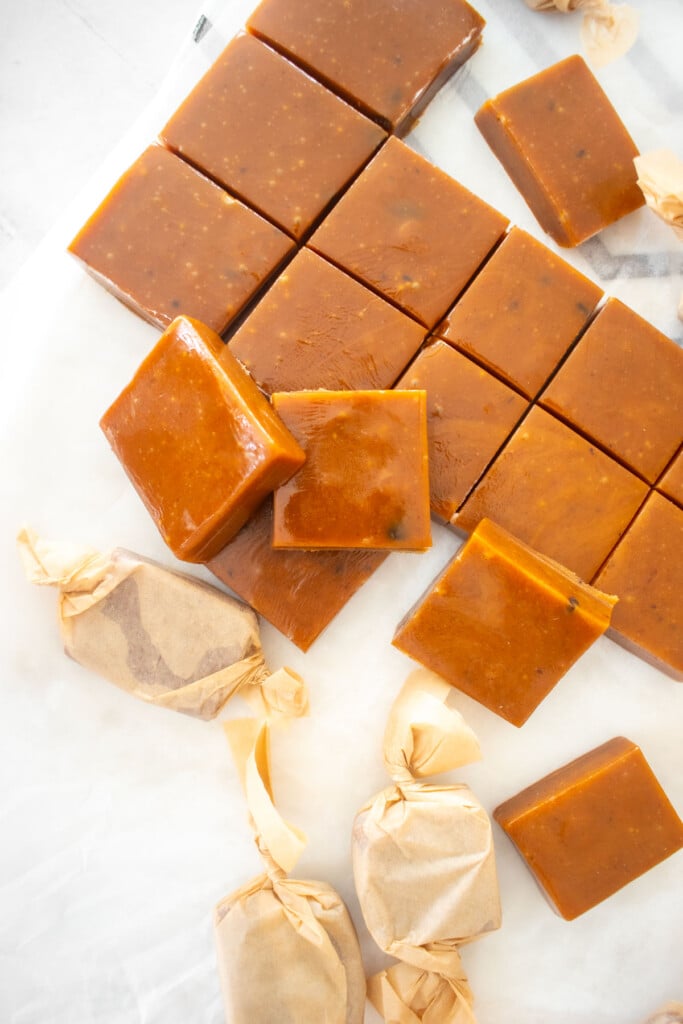 homemade chewy coffee caramel candies cut into squares on a white marble cutting board.