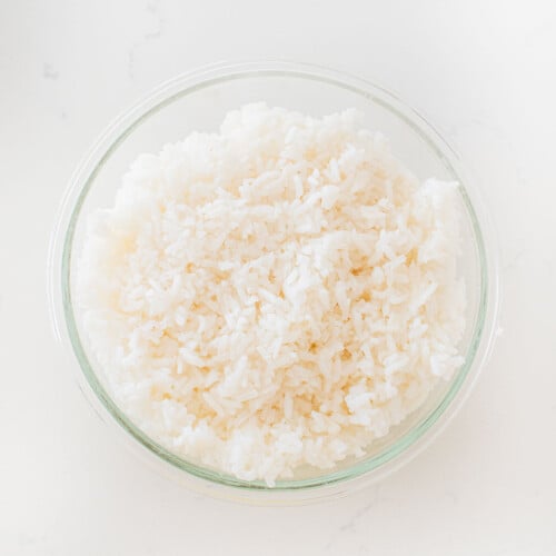 white rice in a glass tupperware on a white marble counter.