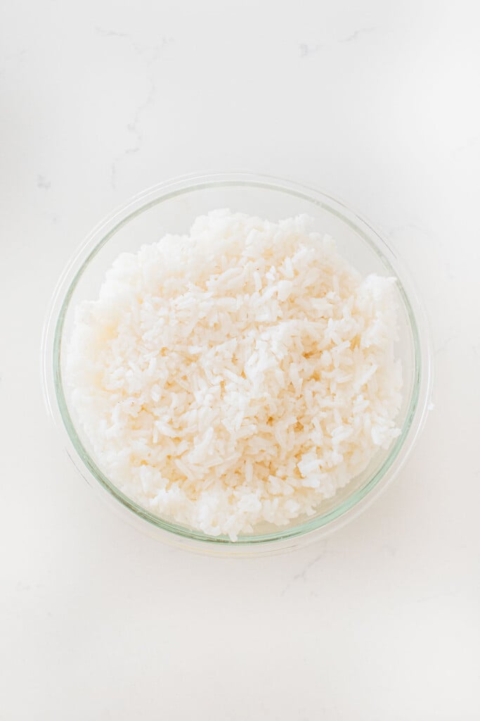 white rice in a glass tupperware on a white marble counter.