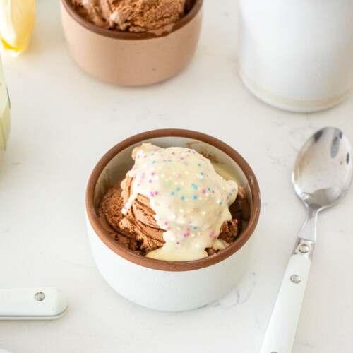 small dish of chocolate ice cream with homemade funfetti magic shell on a marble counter.