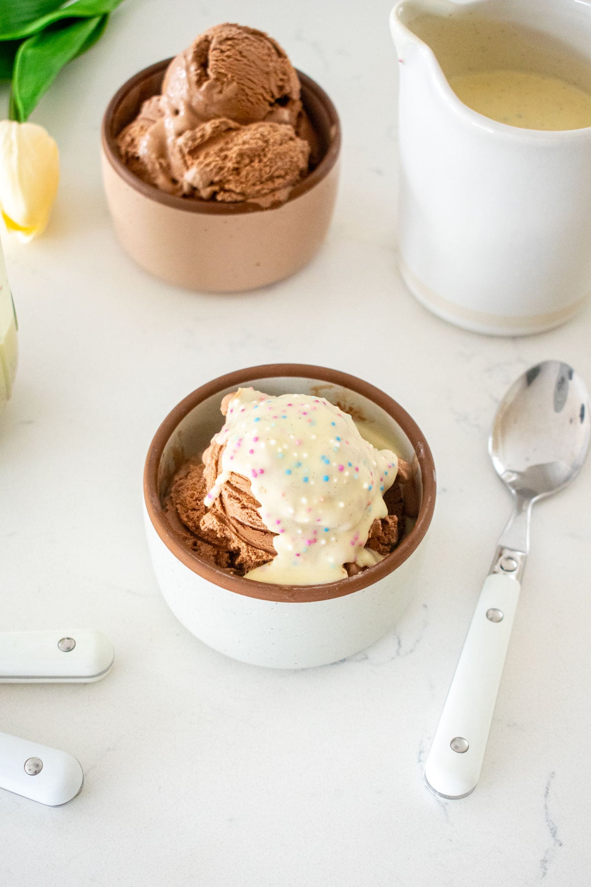 small dish of chocolate ice cream with homemade funfetti magic shell on a marble counter.