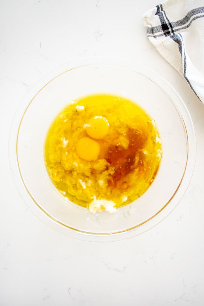 wet ingredients for banana dog cake in a glass mixing bowl on a marble counter.