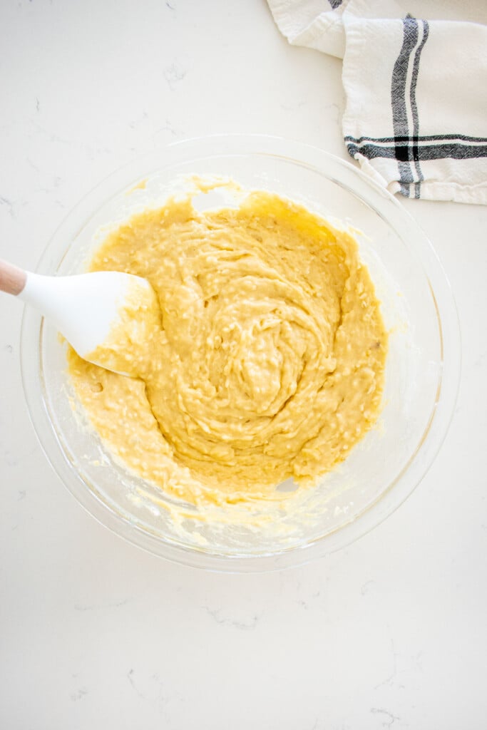 banana dog cake batter in a glass mixing bowl being mixed with a spatula.