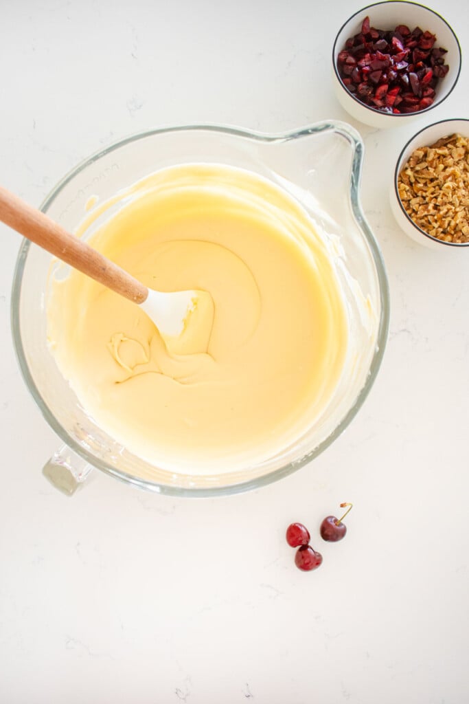 smooth and creamy palmer house ice cream base in a glass mixing bowl with a spatula on a marble counter.