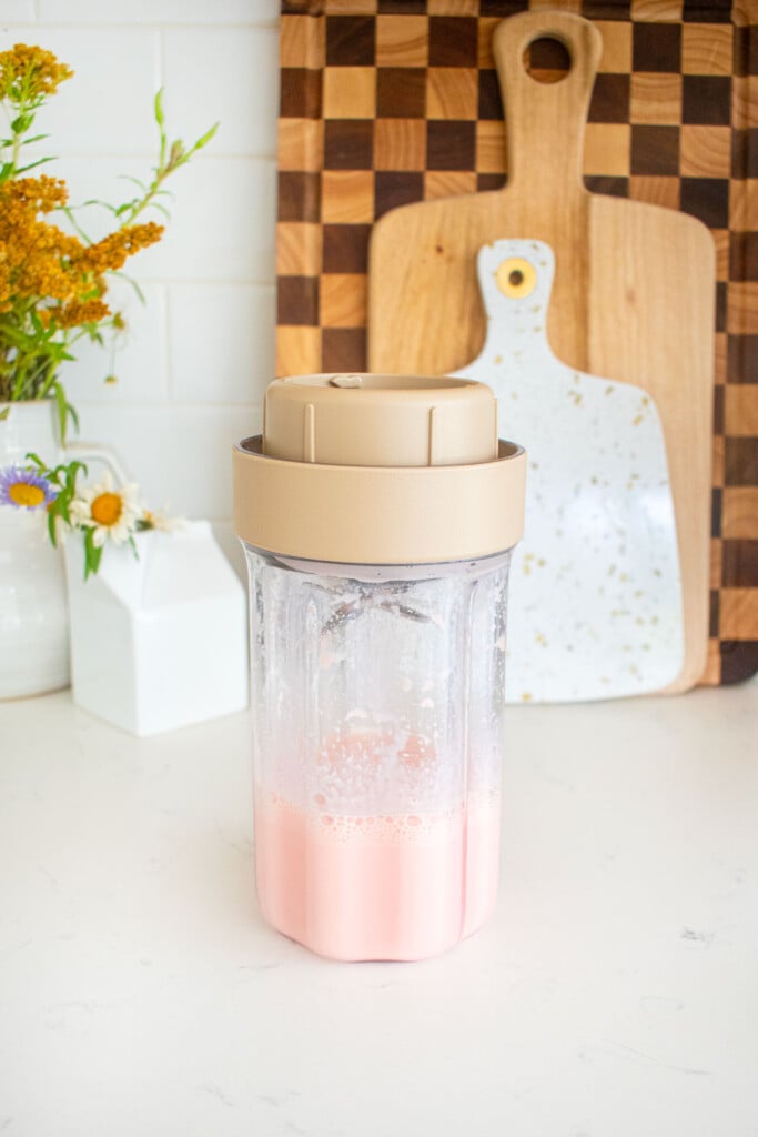 blended greek yogurt and watermelon in a smoothie blender on a marble counter.