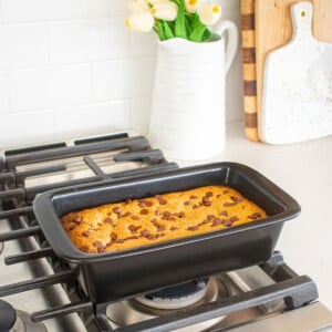 xtrema loaf pan with banana chocolate chip cookie bars baked inside cooling on top of an oven.