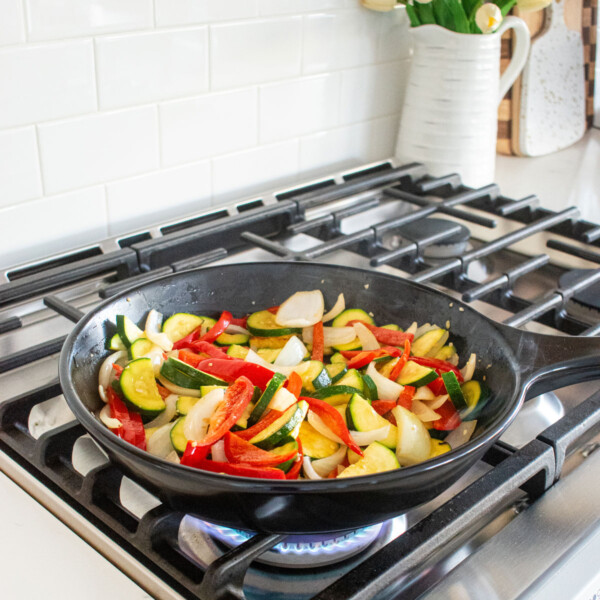 xtrema skillet with sauted vegetables cooking on a gas stoveop.