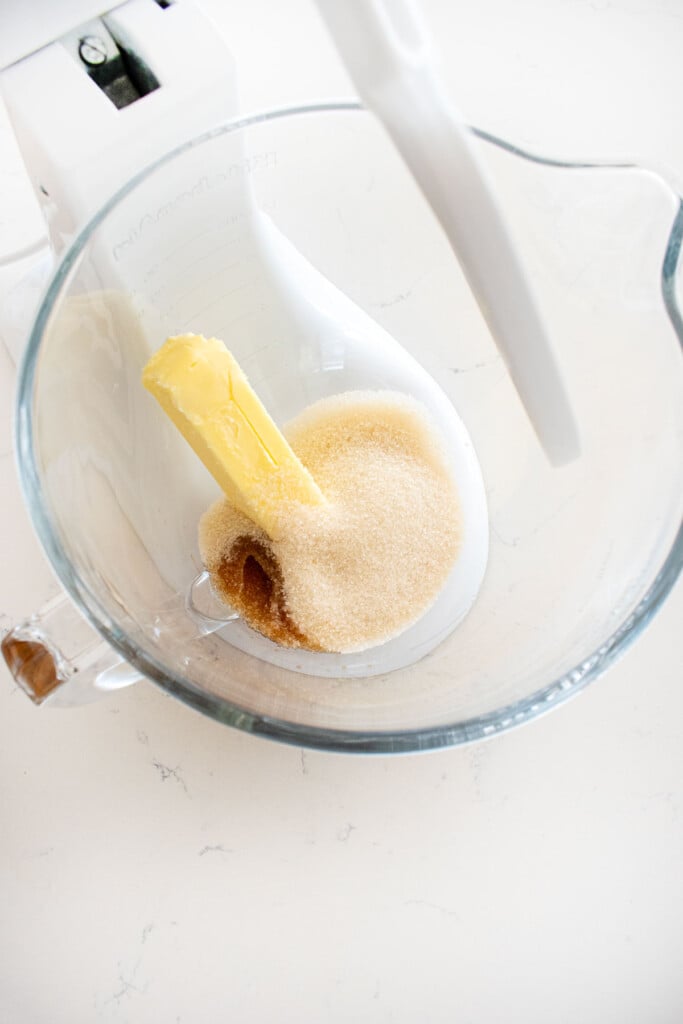 butter sugar and vanilla extract in a glass mixing bowl on a marble counte.r