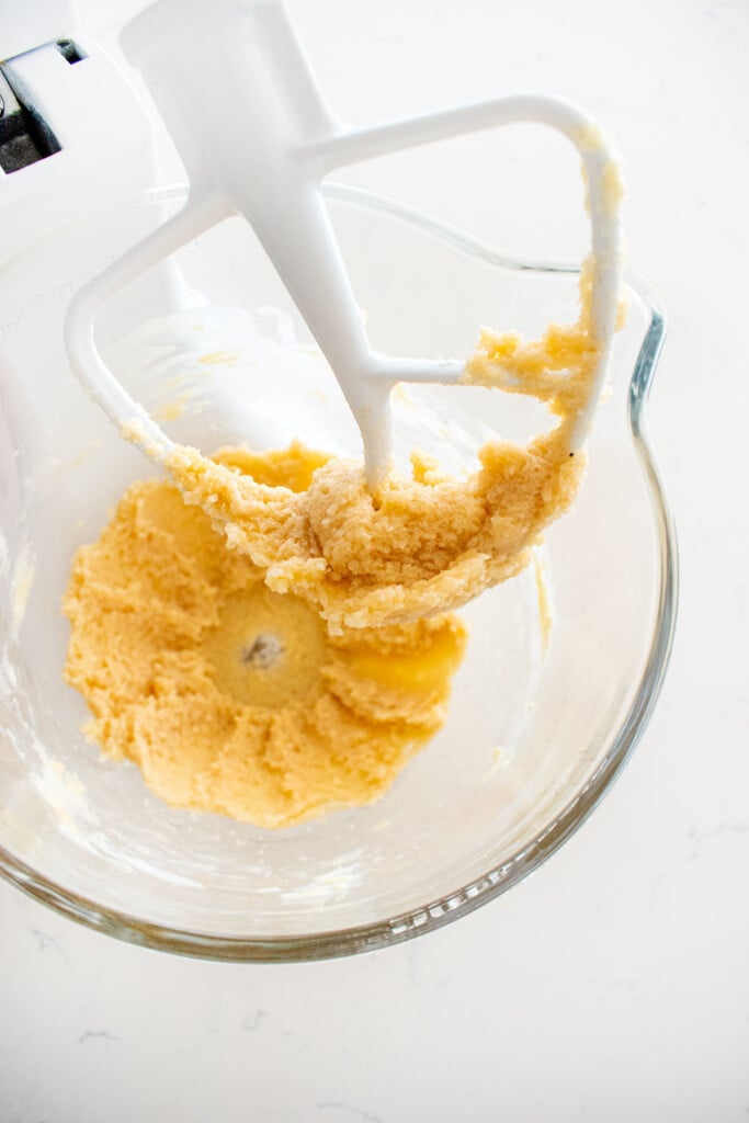 creamed butter and sugar in a glass mixing bowl on a marble counter.
