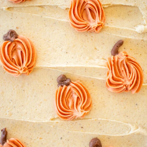 up close of pumpkin spice buttercream frosting with orange buttercream pumpkins piped onto it with small stems.