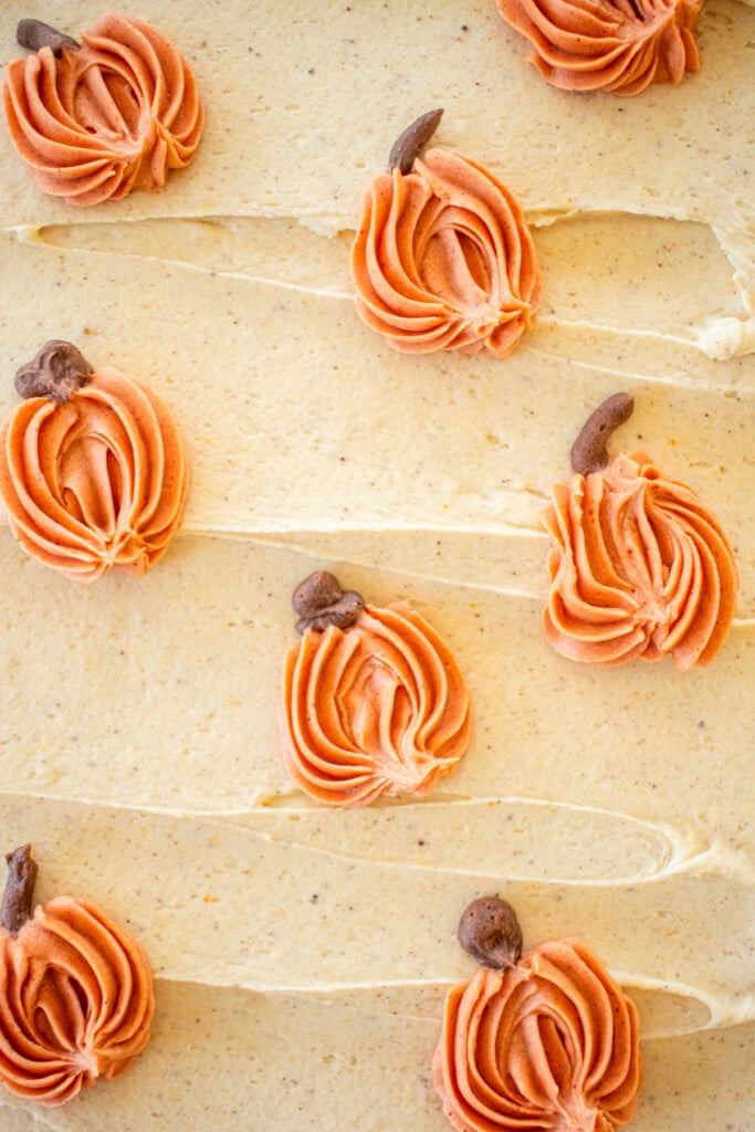 up close of pumpkin spice buttercream frosting with orange buttercream pumpkins piped onto it with small stems.