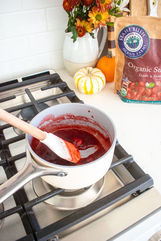 strawberry compote being cooked over the stovetop with a spatula.