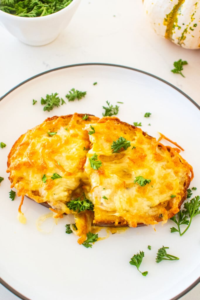 plate of cheesy pumpkin garlic bread with fresh parsley on a marble counter.