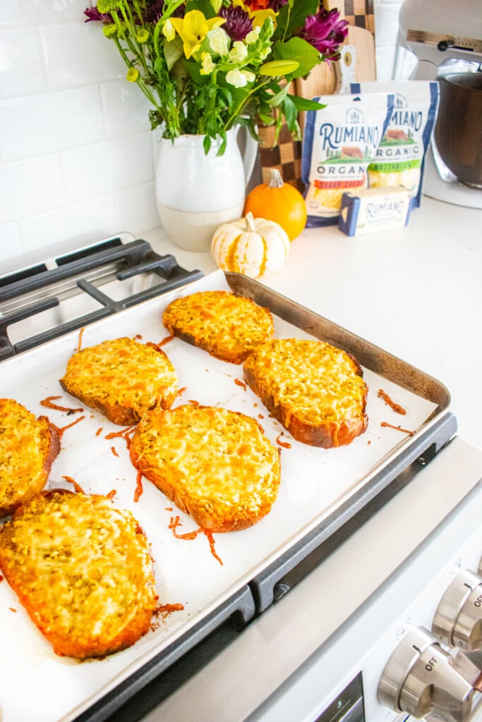 baking sheet with cheesy pumpkin bread cooling on top of an oven.
