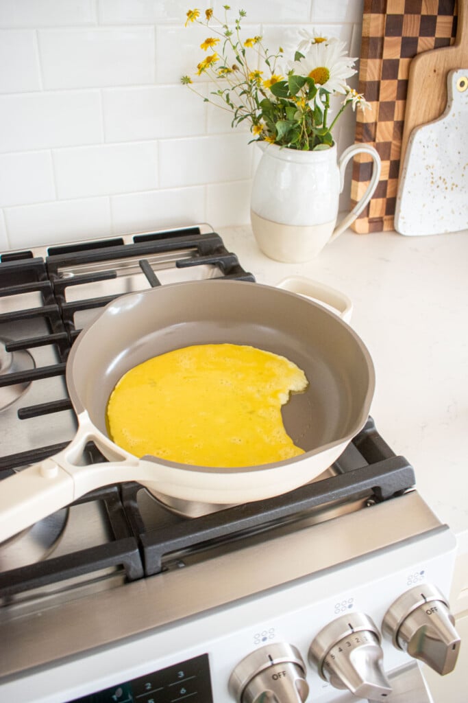 large skillet on a stovetop with eggs cooking.