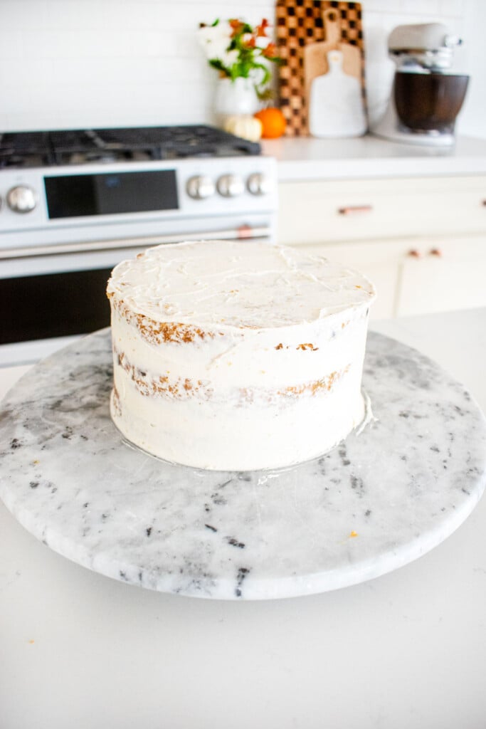 crumb coated cake on a marble turn table on the kitchen counter.