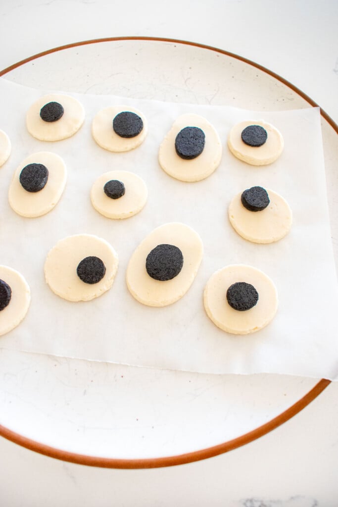monster eyes piped onto a piece of parchment paper on a plate on a marble counter.